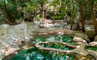 Natural hot spring pools surrounded by lush greenery in Krabi, Thailand.