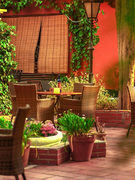 Outdoor seating area at Tablao flamenco Jardines de Zoraya with wicker chairs and lush greenery.