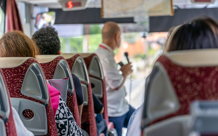 Tourists on a bus listening to a guide on the Appian Way tour in Rome, Italy.