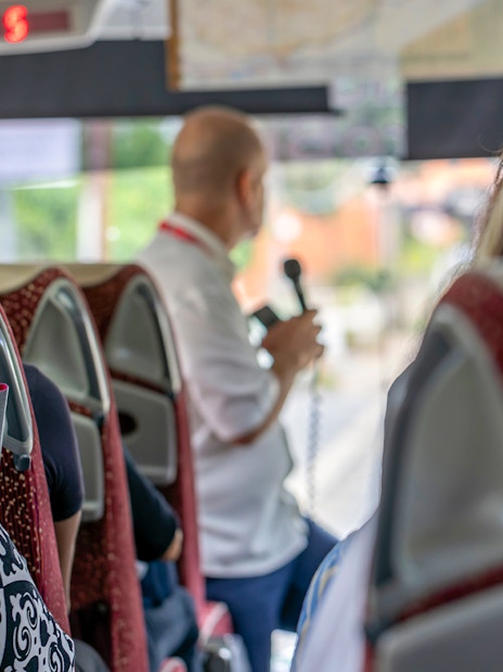 Tourists on a bus listening to a guide on the Appian Way tour in Rome, Italy.