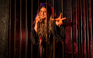 Witch role-playing behind bars at London Dungeon.