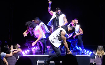 Chippendales performers on stage during a live act, engaging with the audience.