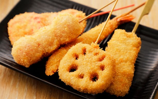 Assorted kushikatsu skewers on a black plate, Osaka Night Food Tour.