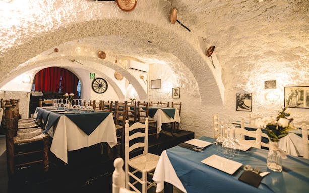 Dining area at Venta el Gallo with set tables and rustic decor, Granada Flamenco Show.