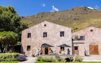Winery visitors enjoying a tasting outside a rustic building in Queenstown.