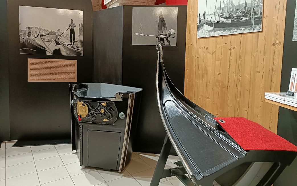 Gondola exhibit at Doge's Palace, Venice, featuring historical photos and decorative details.