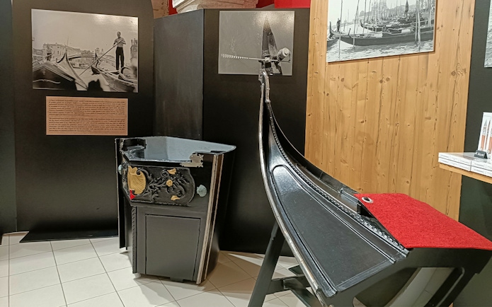 Gondola exhibit at Doge's Palace, Venice, featuring historical photos and decorative details.