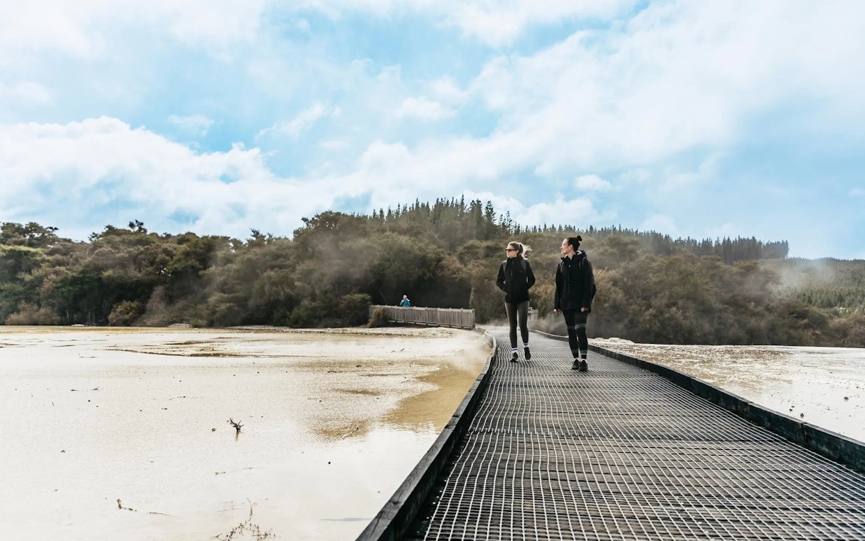 Visitors walking on a boardwalk at Wai-O-Tapu Thermal Wonderland, New Zealand.