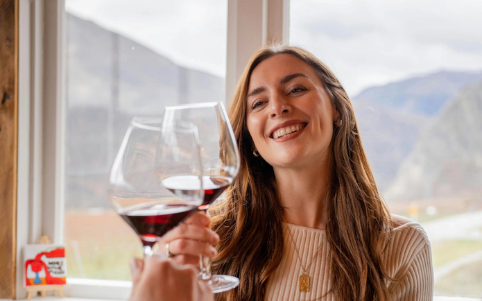 Toasting with red wine during a Queenstown wine tour.
