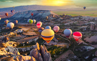 Hot air balloons over Cappadocia's unique rock formations at sunrise.