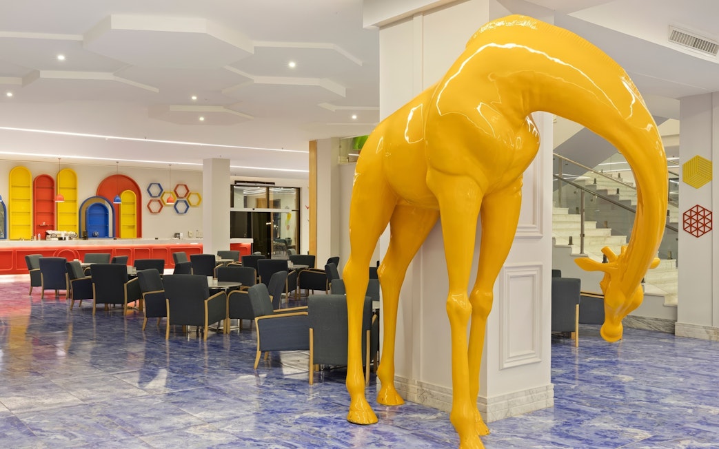 Dining area with colorful decor and yellow giraffe sculpture, Neverland Waterpark, Pickalbatros, Hurghada.