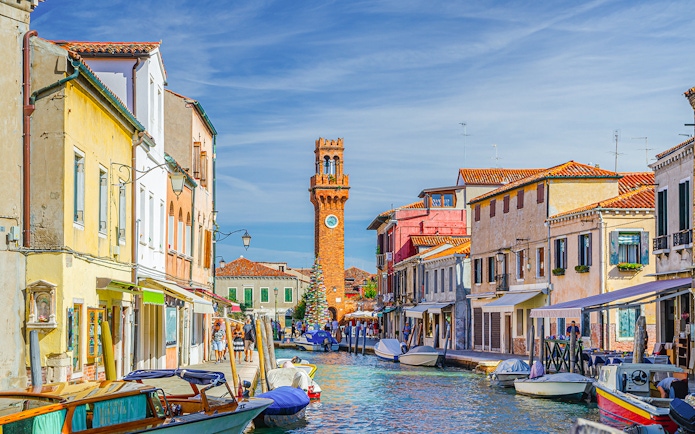 Murano canal with Torre dell'Orologio clock tower and colorful buildings.