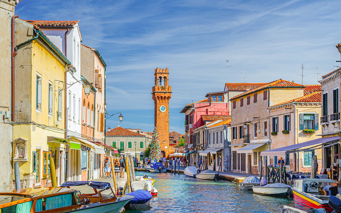 Murano canal with Torre dell'Orologio clock tower and colorful buildings.
