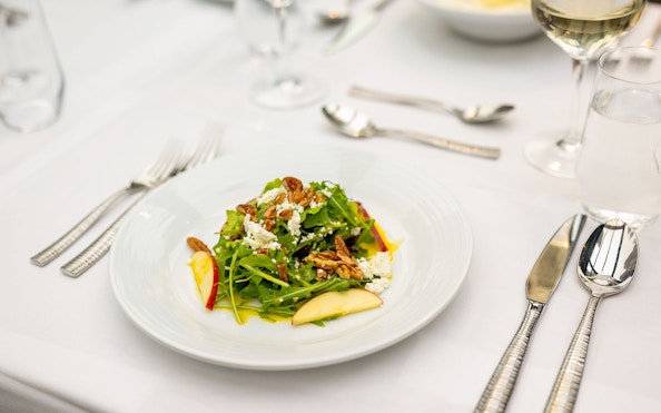 Salad with pecans and apple slices on a white table setting during Bateaux New York Premier Lunch Cruise.