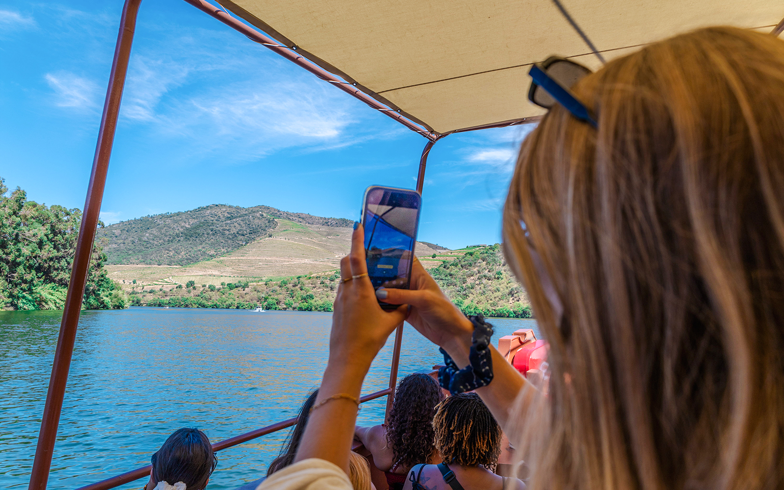 Guests enjoying a boat ride on the Douro River, Portugal, capturing vineyard views.
