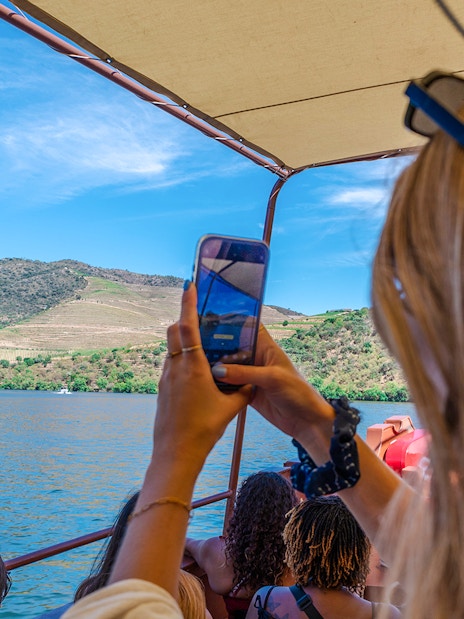 Guests enjoying a boat ride on the Douro River, Portugal, capturing vineyard views.
