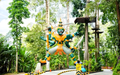 Entrance statue of Hanuman Luge surrounded by lush forest in Thailand.