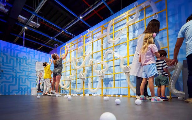 Children engaging with interactive tubes at Chaos Lab exhibit.