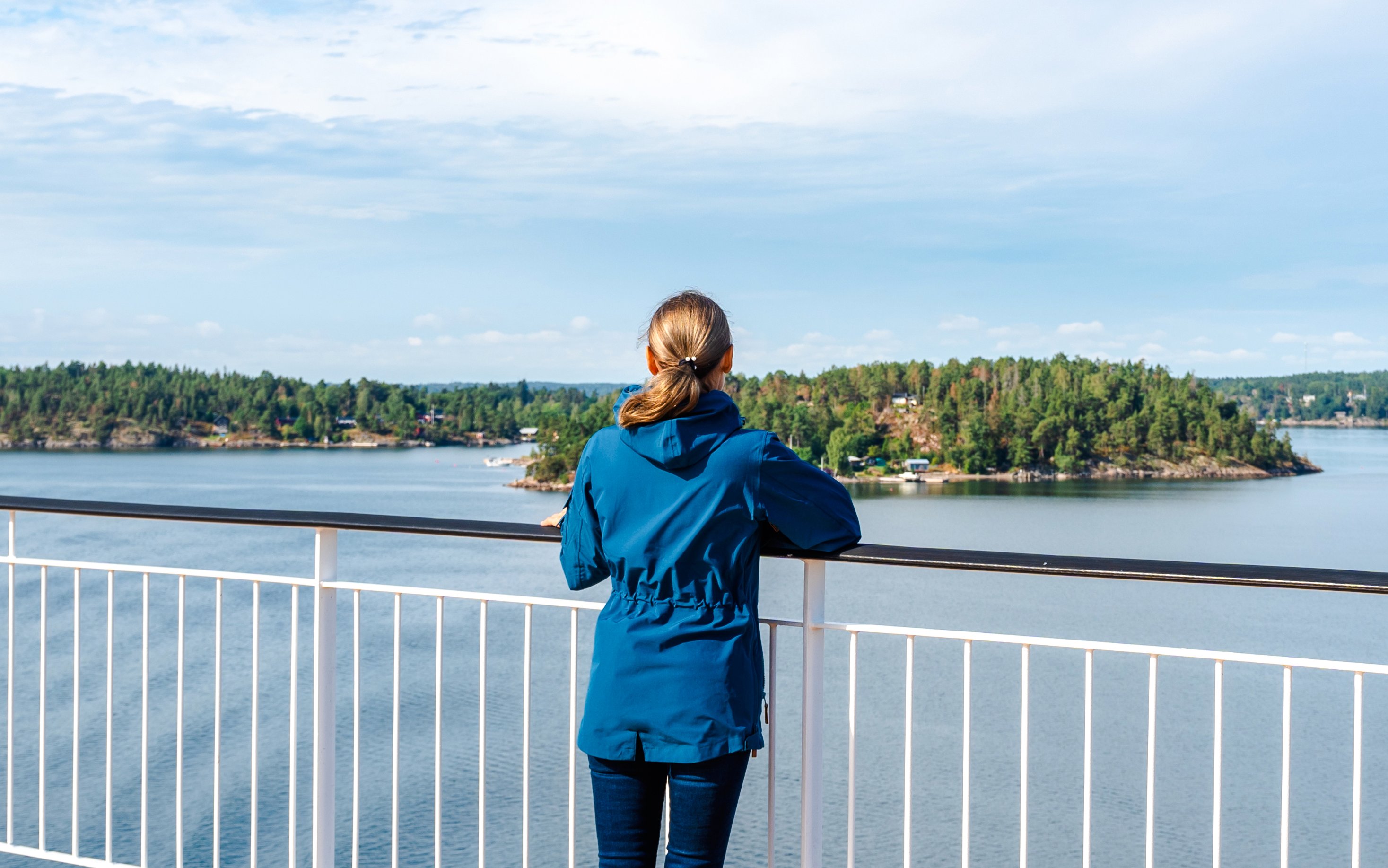 Woman on ferry deck overlooking Stockholm archipelago.
