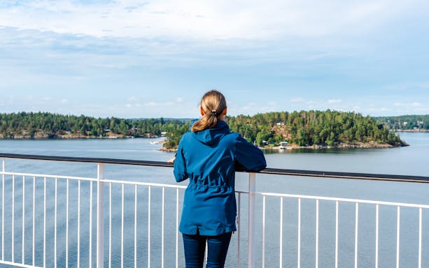 Woman on ferry deck overlooking Stockholm archipelago.
