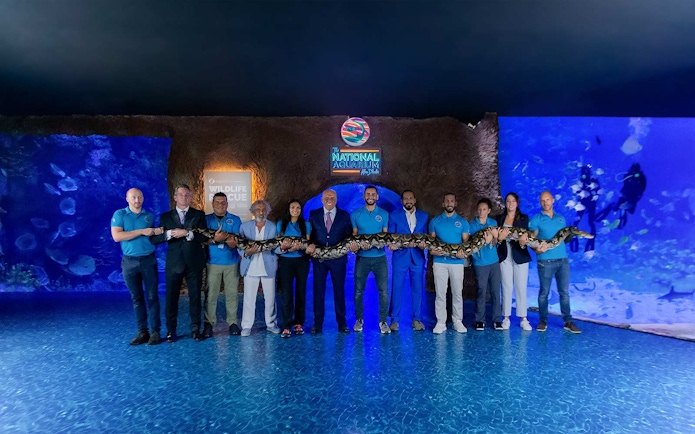 Group holding a large snake at the National Aquarium Abu Dhabi.