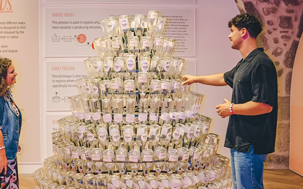 Visitors exploring a wine bottle display at the Pink Palace.