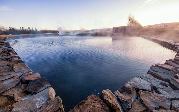 Secret Lagoon hot spring surrounded by stone walls in Gamla Laugin, Iceland.