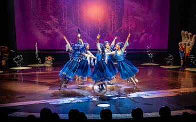 Performers in blue costumes ride unicycles in a theatrical show, "Drawn to Life.