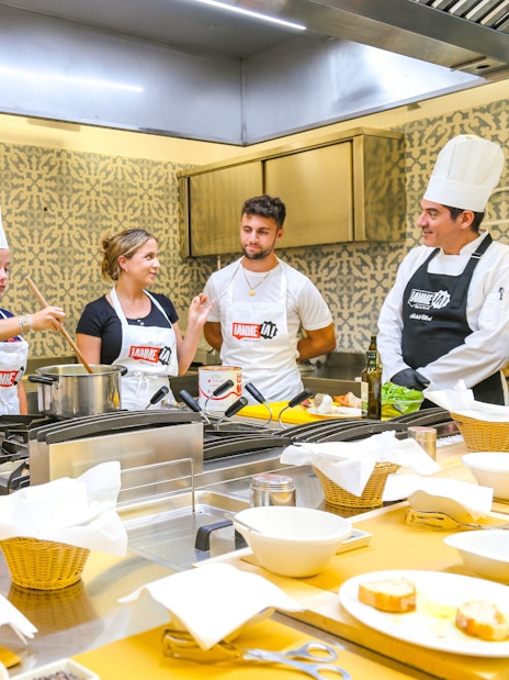 Tourists learning to cook with a chef at Neapolitan Cooking School in Sorrento.