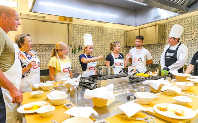 Tourists learning to cook with a chef at Neapolitan Cooking School in Sorrento.