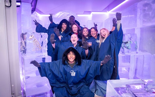 Group enjoying IceBar Surfers Paradise in winter coats, surrounded by ice sculptures.