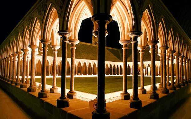 Mont-Saint-Michel Abbey cloister illuminated at night during immersive tour.