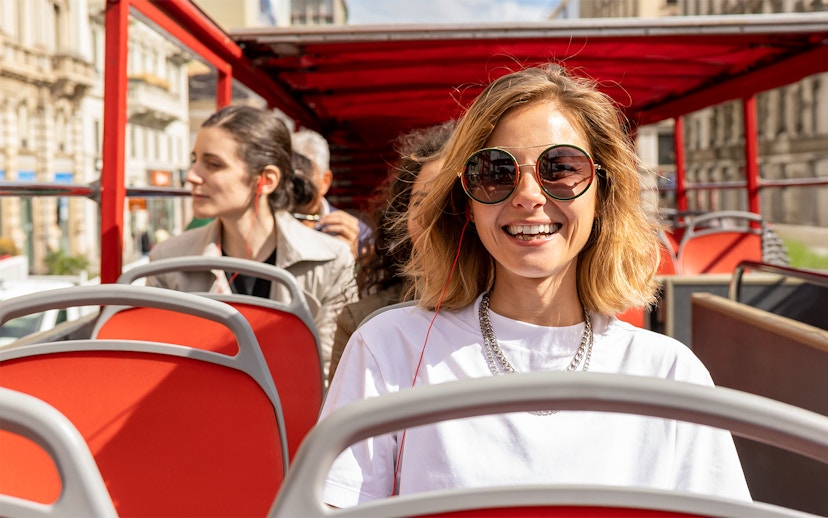 Woman enjoying audio guide on Milan Hop On Hop Off bus tour.
