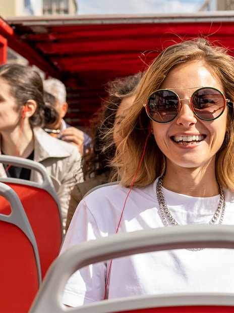Woman enjoying audio guide on Milan Hop On Hop Off bus tour.