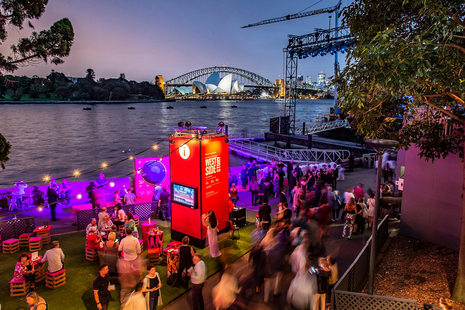 Crowd gathering for West Side Story on Sydney Harbour with Opera House and Harbour Bridge in view.