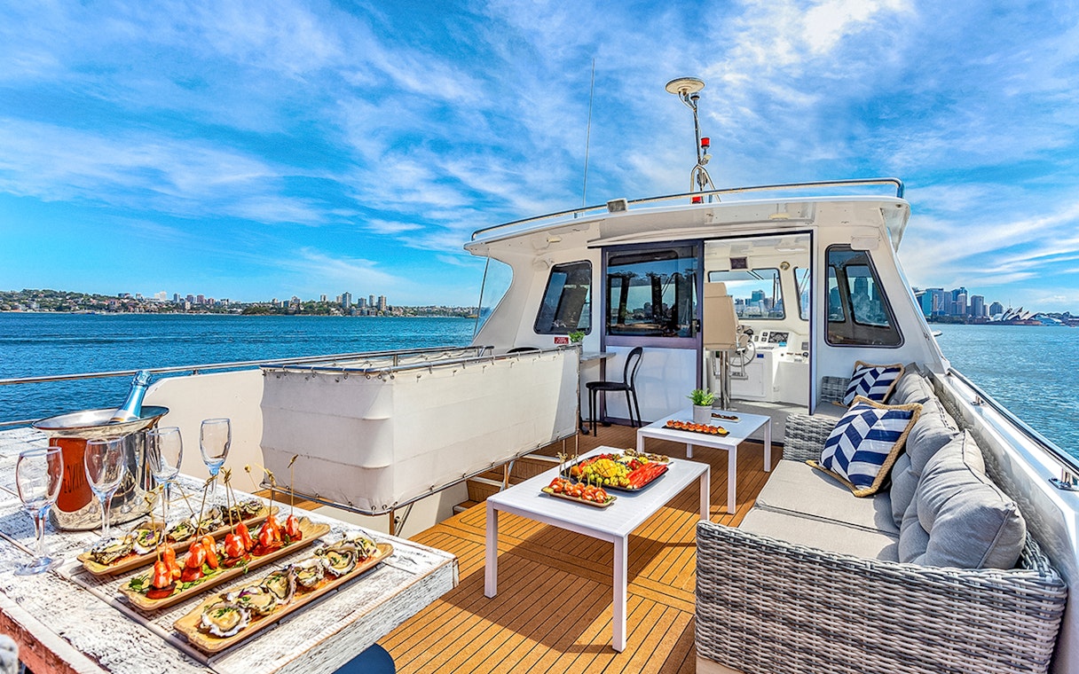 Luxurious yacht deck with gourmet appetizers and Sydney skyline view during Vivid Sydney cruise.