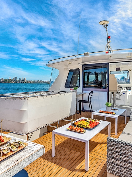 Luxurious yacht deck with gourmet appetizers and Sydney skyline view during Vivid Sydney cruise.