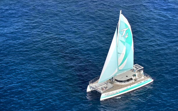 Sailboat on a luxury snorkel tour in Maui, Hawaii, cruising over clear blue ocean waters.