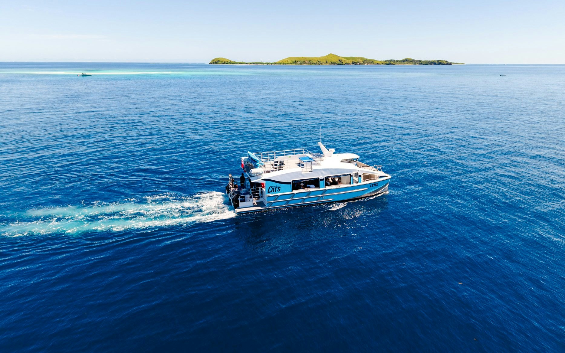 Catamaran cruising near a small island, South Sea Cats, Fiji.