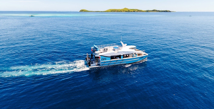 Catamaran cruising near a small island, South Sea Cats, Fiji.