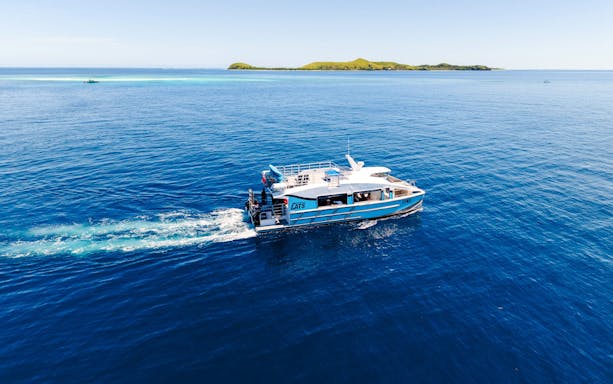 Catamaran cruising near a small island, South Sea Cats, Fiji.