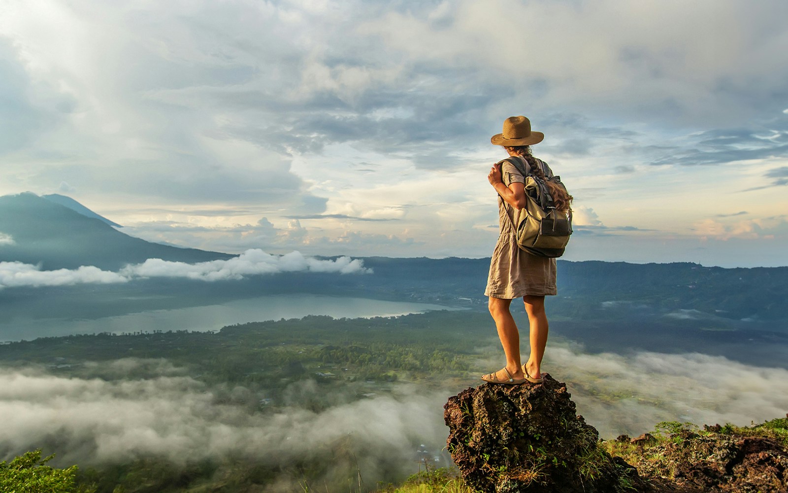 Woman enjoying sunrise from a top of mountain Batur, Bali