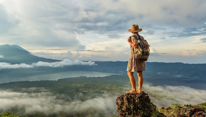Woman enjoying the sunrise from the top of mountain Batur, Bali