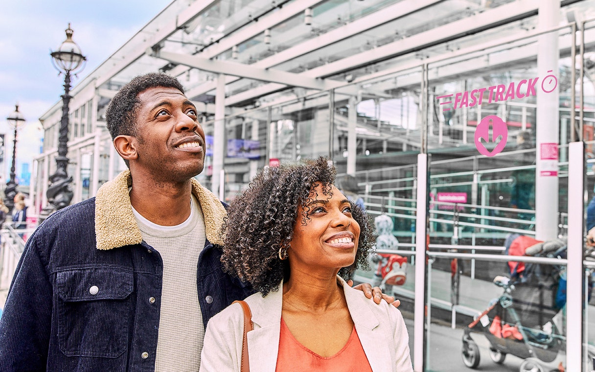 Couple smiling near Fast Track entrance to the London Eye.