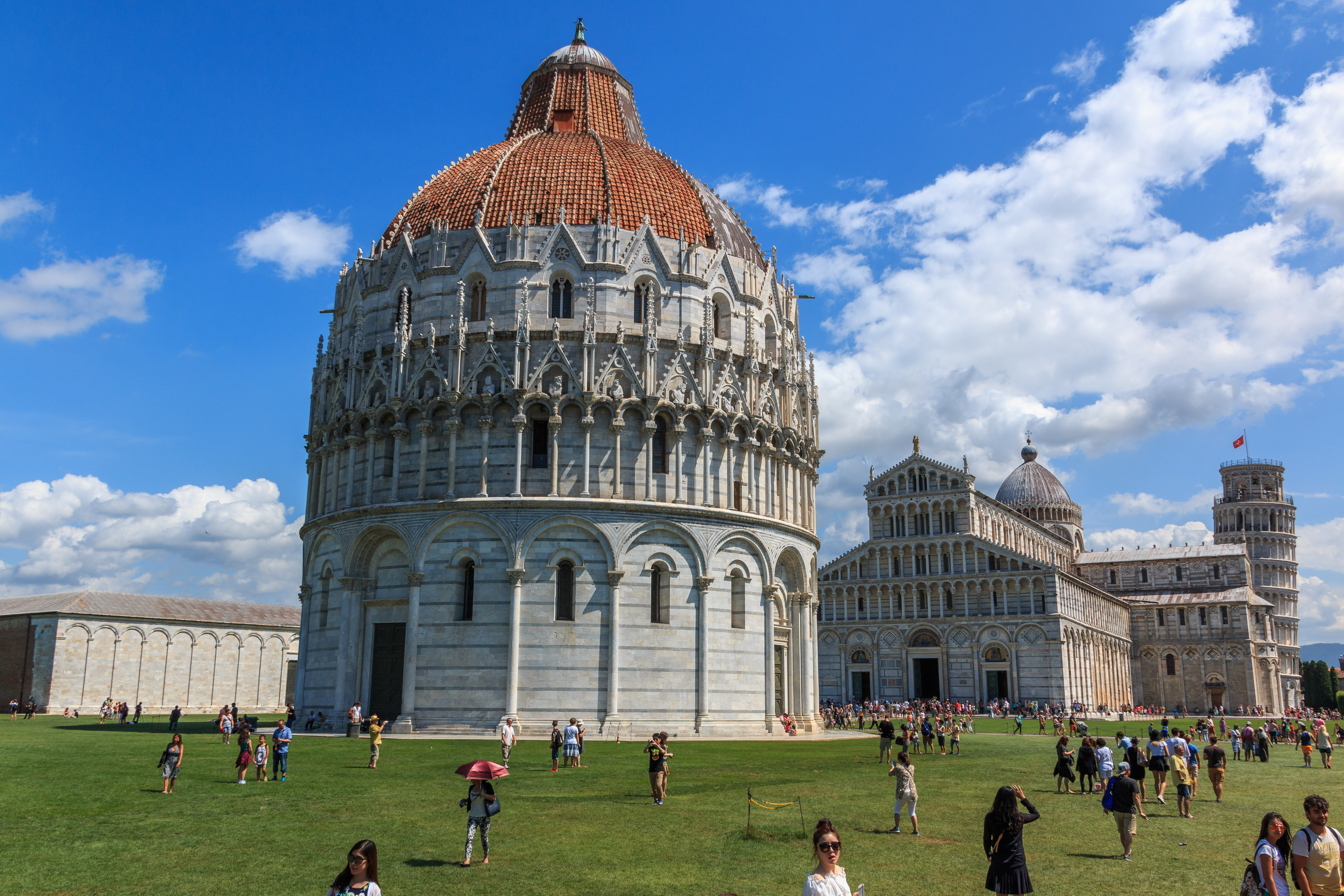 Pisa Baptistery with tourists on the lawn, Pisa, Italy.