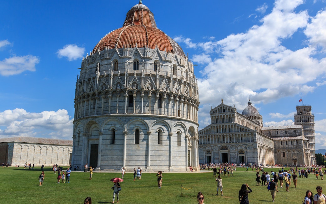 Pisa Baptistery with tourists on the lawn, Pisa, Italy.