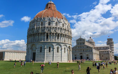 Pisa Baptistery with tourists on the lawn, Pisa, Italy.