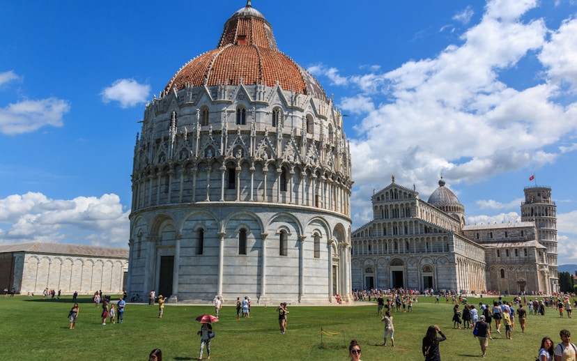 Pisa Baptistery with tourists on the lawn, Pisa, Italy.