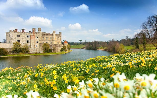 Leeds Castle surrounded by a moat and blooming daffodils in Kent, England.