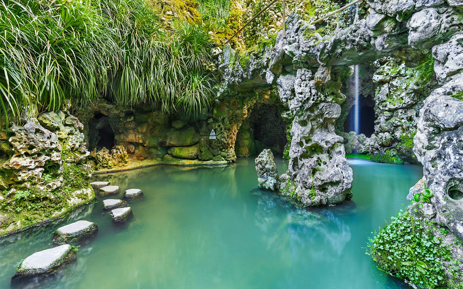 Sintra's Quinta da Regaleira garden with tourists exploring the ornate stone well.
